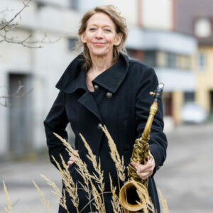 Veronica Reiff - Die Saxophonistin Veronica Reiff steht mit einem wunderschönen Bonn Alt Saxophon vor einer Häuserwand.